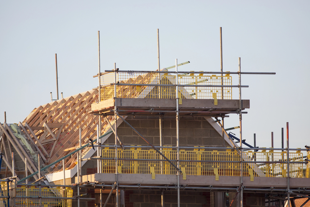 A house under construction, surrounded by scaffolding, showcasing the building process and materials used.
