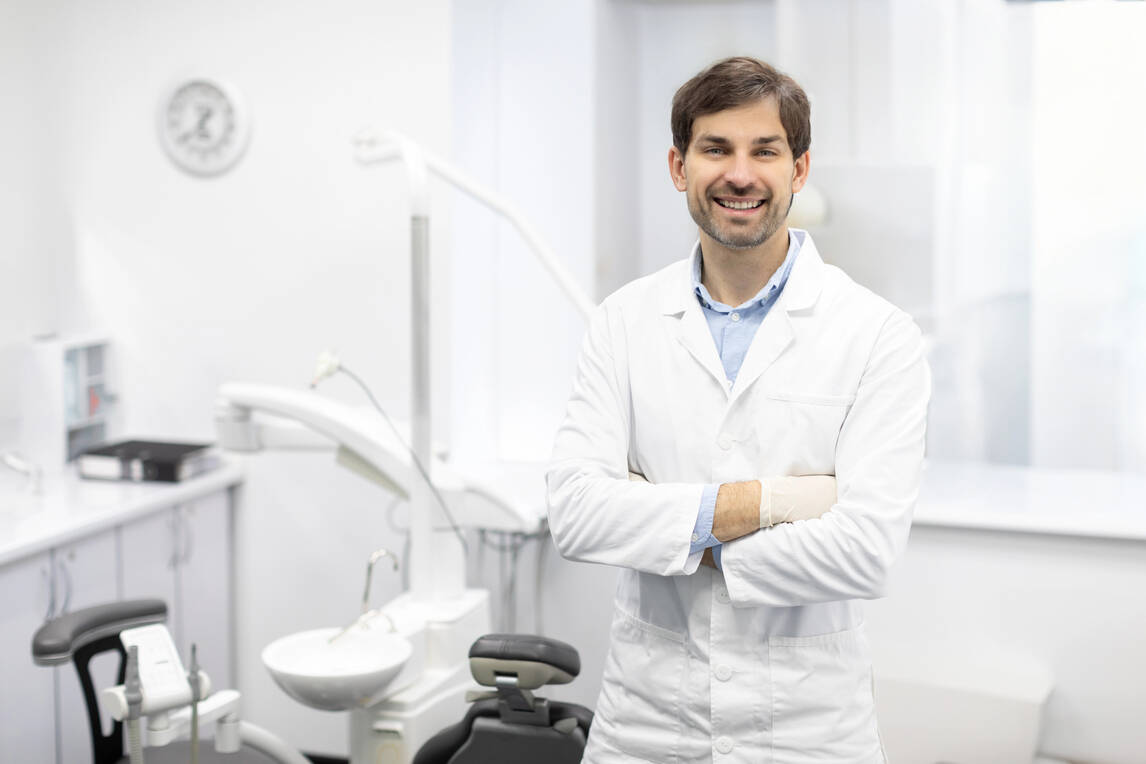 A cheerful man in a dental office, showcasing a friendly environment with dental tools in the background.