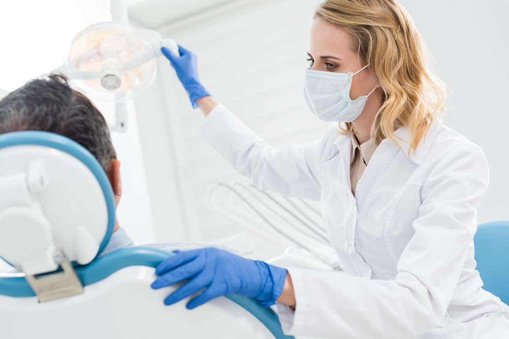 Doctor adjusting lamp in modern dental clinic — Photo